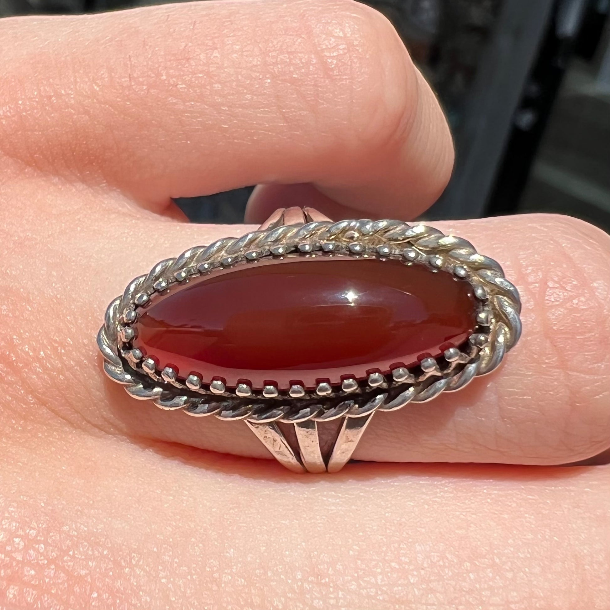 A split shank silver ring set with a brown sard stone in a rope bezel with small prongs.