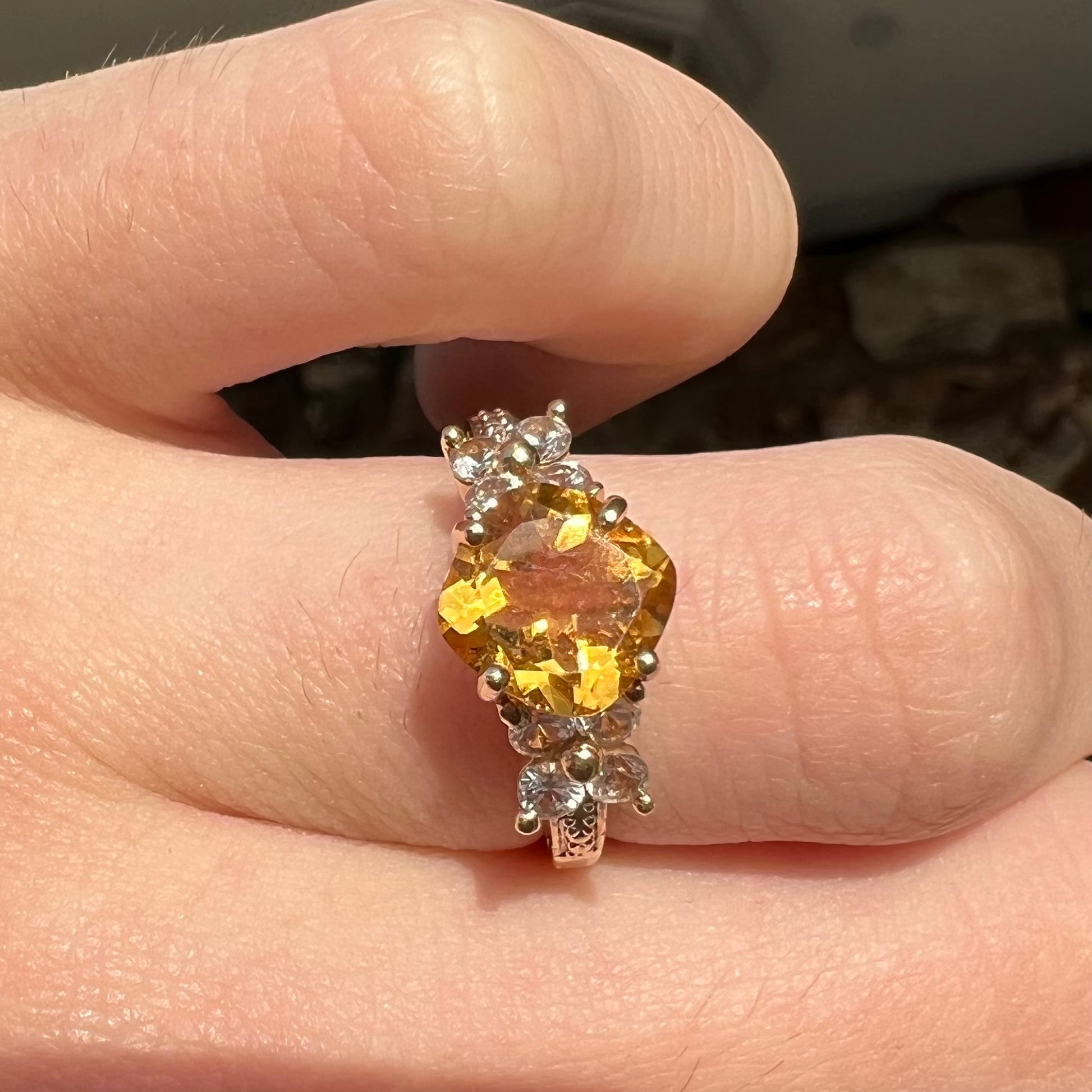 A cushion cut citrine set in a yellow gold ring with four round white sapphires and two diamonds on each side.