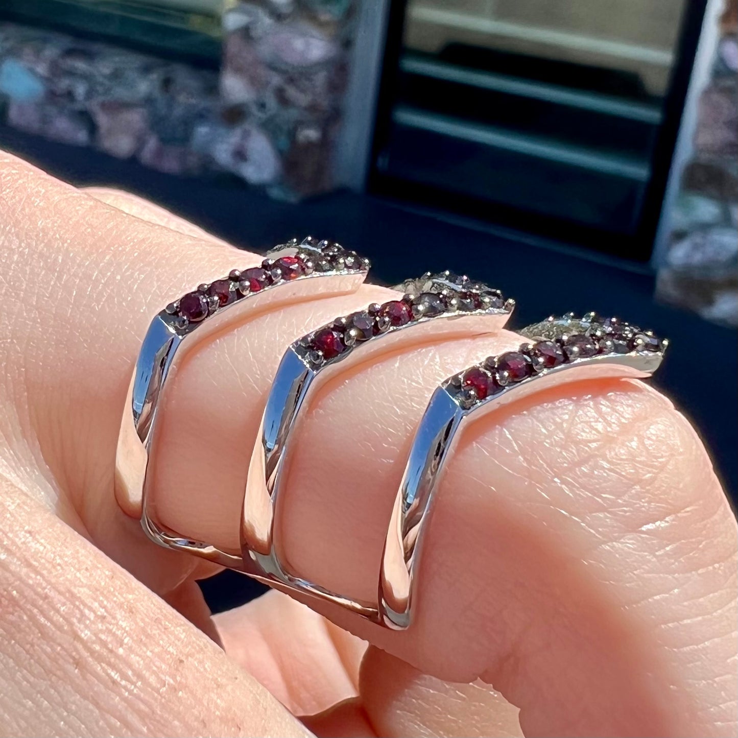 A sterling silver ring pave set with round almandine garnet stones.  The piece appears to be three rings in one.