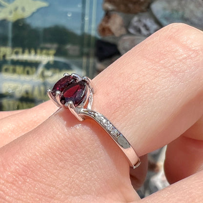 A sterling silver ring set with two faceted heart shape red almandine garnet stones.