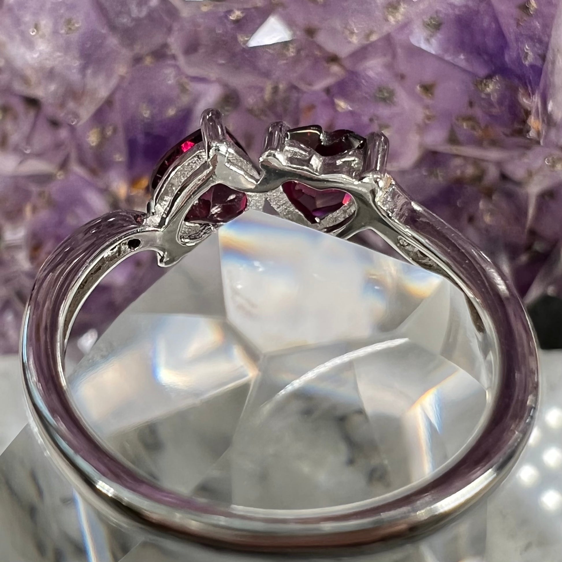 A sterling silver ring set with two faceted heart shape red almandine garnet stones.