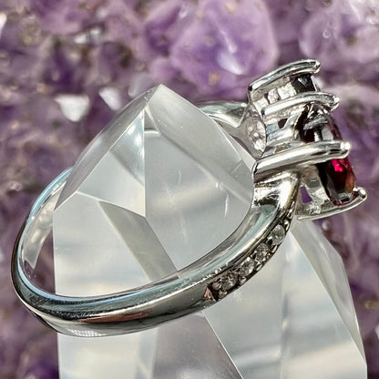 A sterling silver ring set with two faceted heart shape red almandine garnet stones.