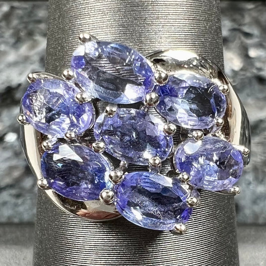 A sterling silver cluster ring prong set with seven faceted oval cut blue tanzanite stones.