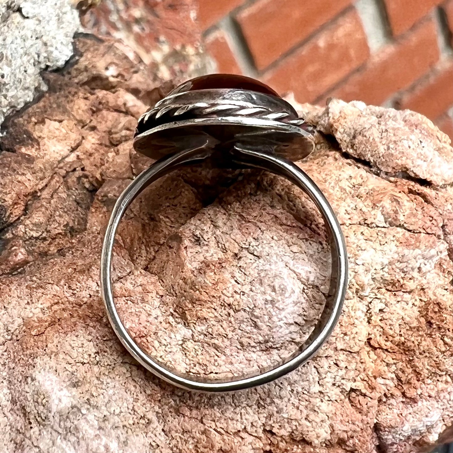 A men's sterling silver rope bezel ring set with a red tiger's eye stone.