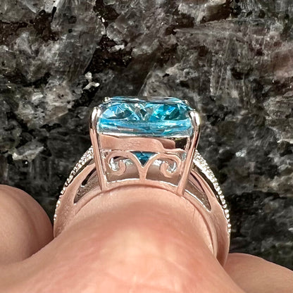 A sterling silver ring prong set with a large, cushion cut sky blue topaz stone.  The shank has been textured to mimic accent stones.