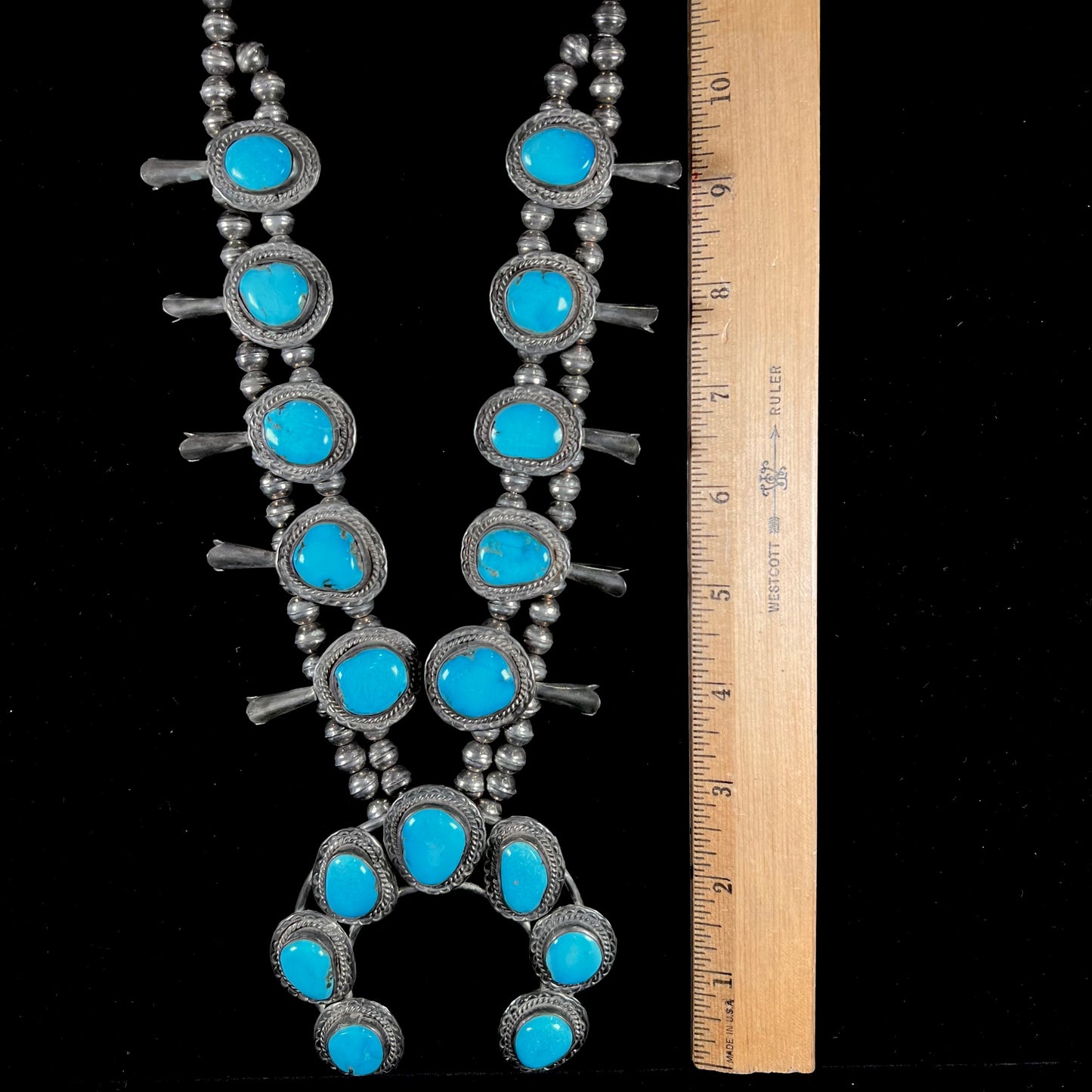 A handmade, sterling silver, Navajo Sleeping Beauty turquoise squash blossom necklace.