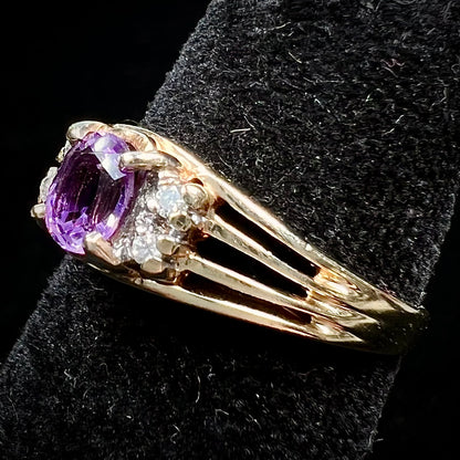 A ladies split shank gold ring set with an oval cut amethyst and round brilliant diamond accents.