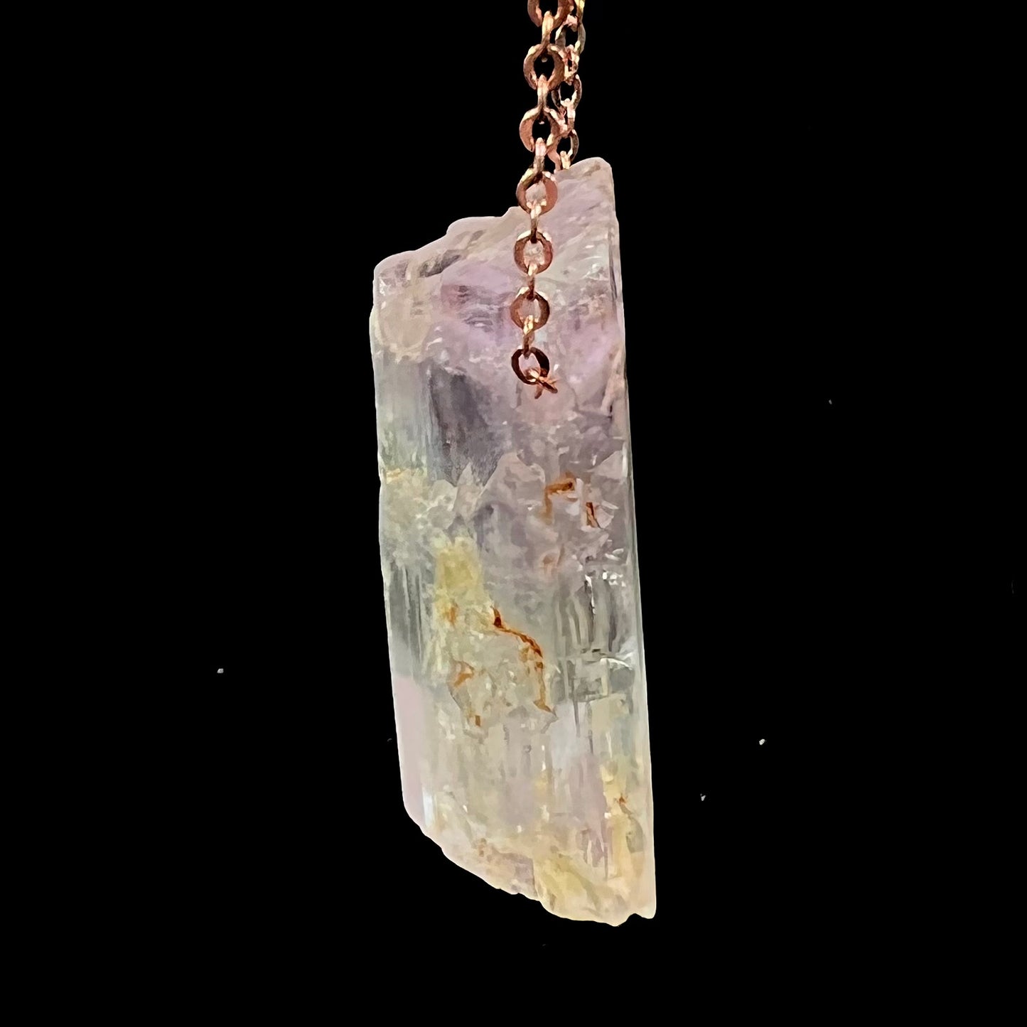 A drilled bicolor spodumene crystal hanging on a copper cable chain.  The crystal is pink and yellow, or kunzite and triphane respectively.