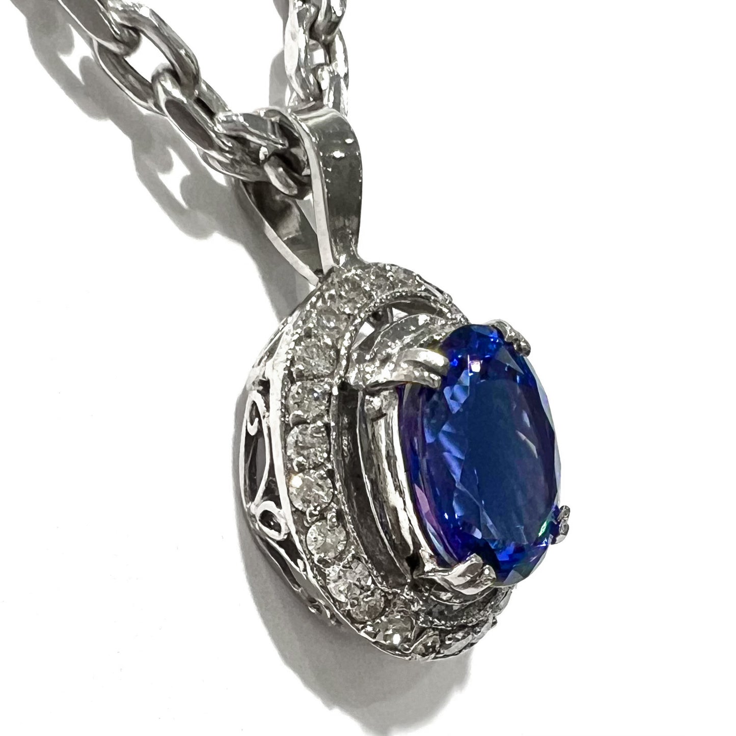 A ladies' 14kt white gold tanzanite and diamond halo pendant.  The sides of the pendant have filigree.