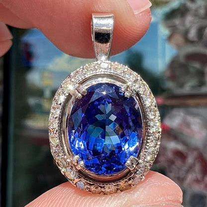 A ladies' 14kt white gold tanzanite and diamond halo pendant.  The sides of the pendant have filigree.