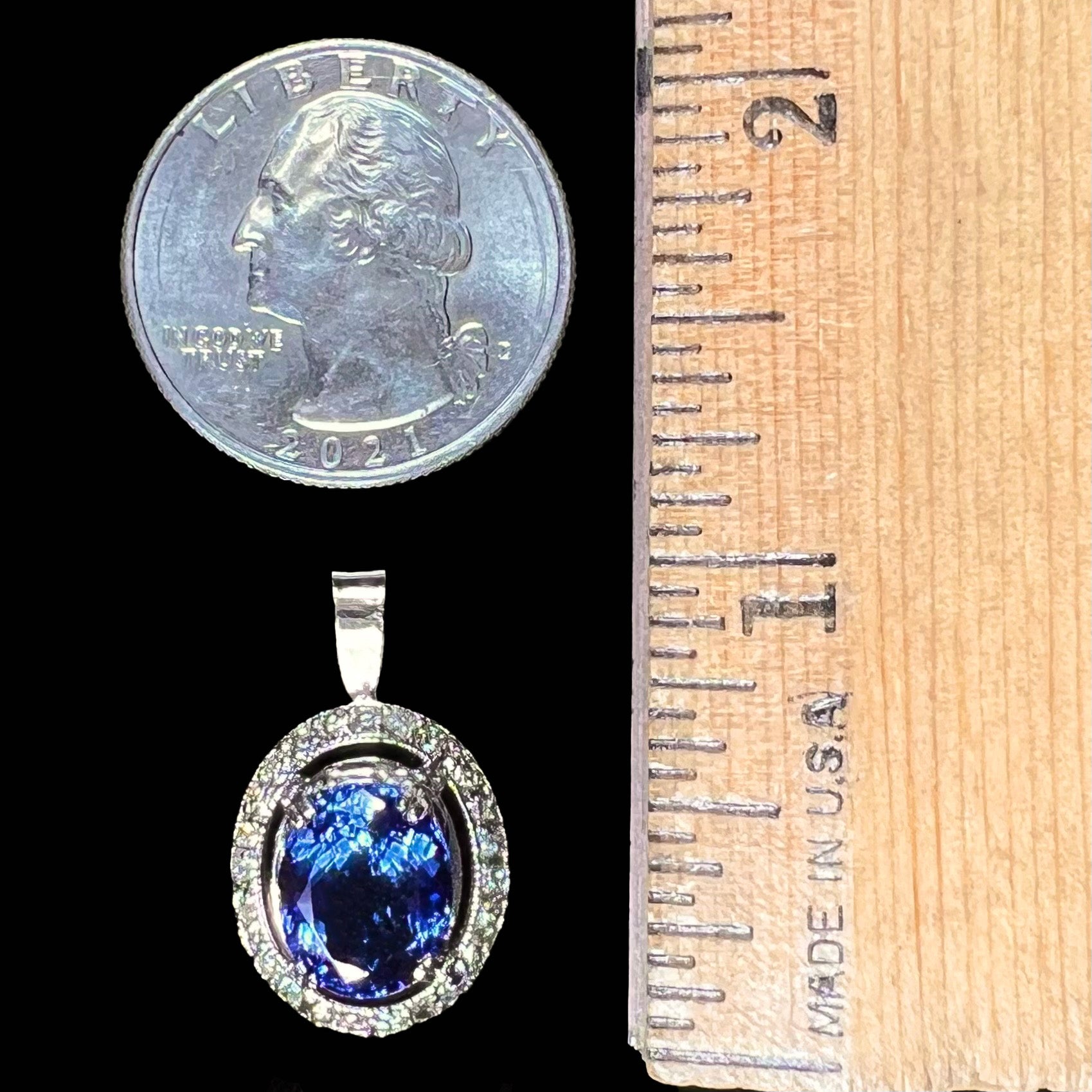 A ladies' 14kt white gold tanzanite and diamond halo pendant.  The sides of the pendant have filigree.