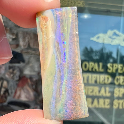 A polished, tapered rectangular cut boulder opal stone from Quilpie, Australia.