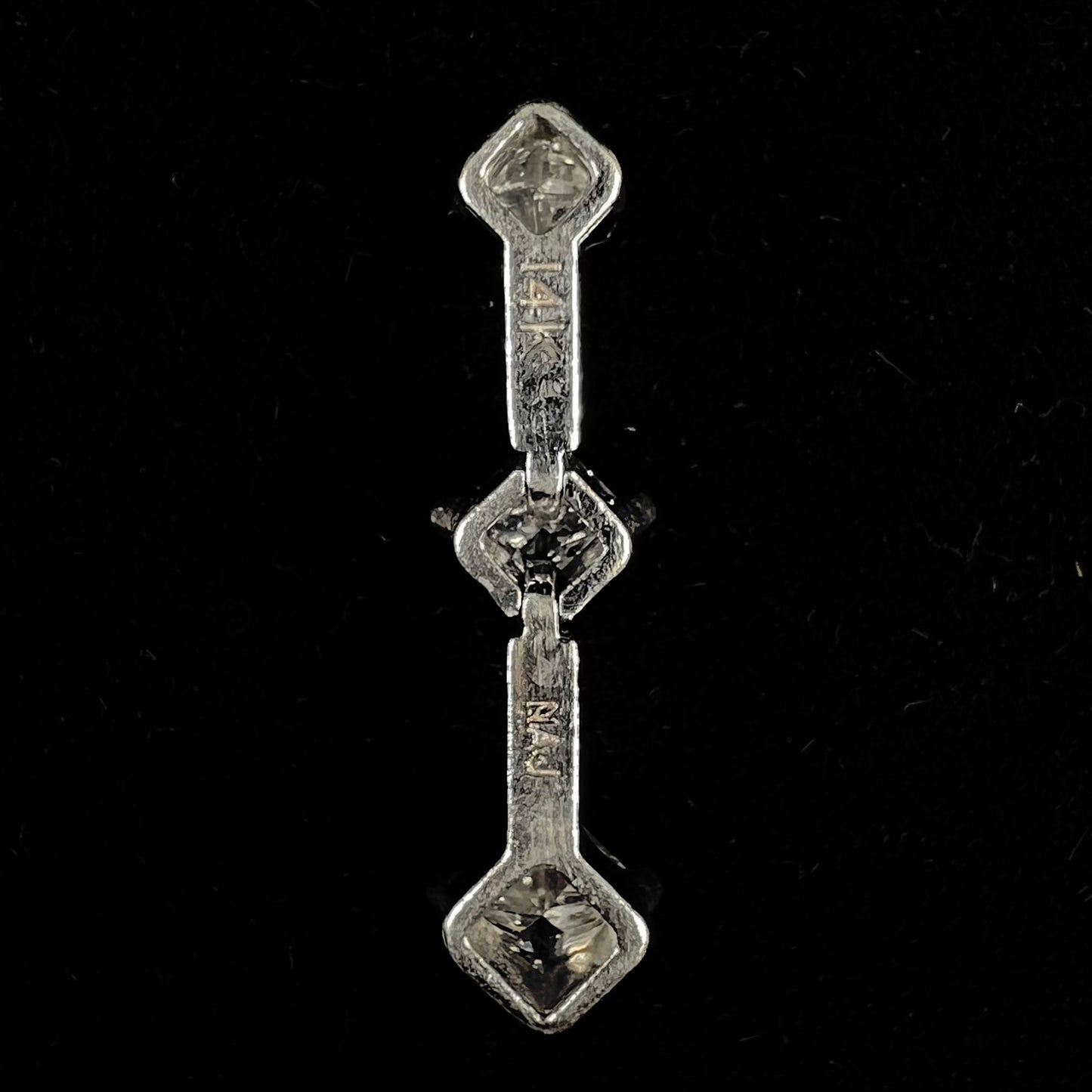 A ladies' white gold three stone drop pendant set with princess cut diamonds.  There are two points of articulation.