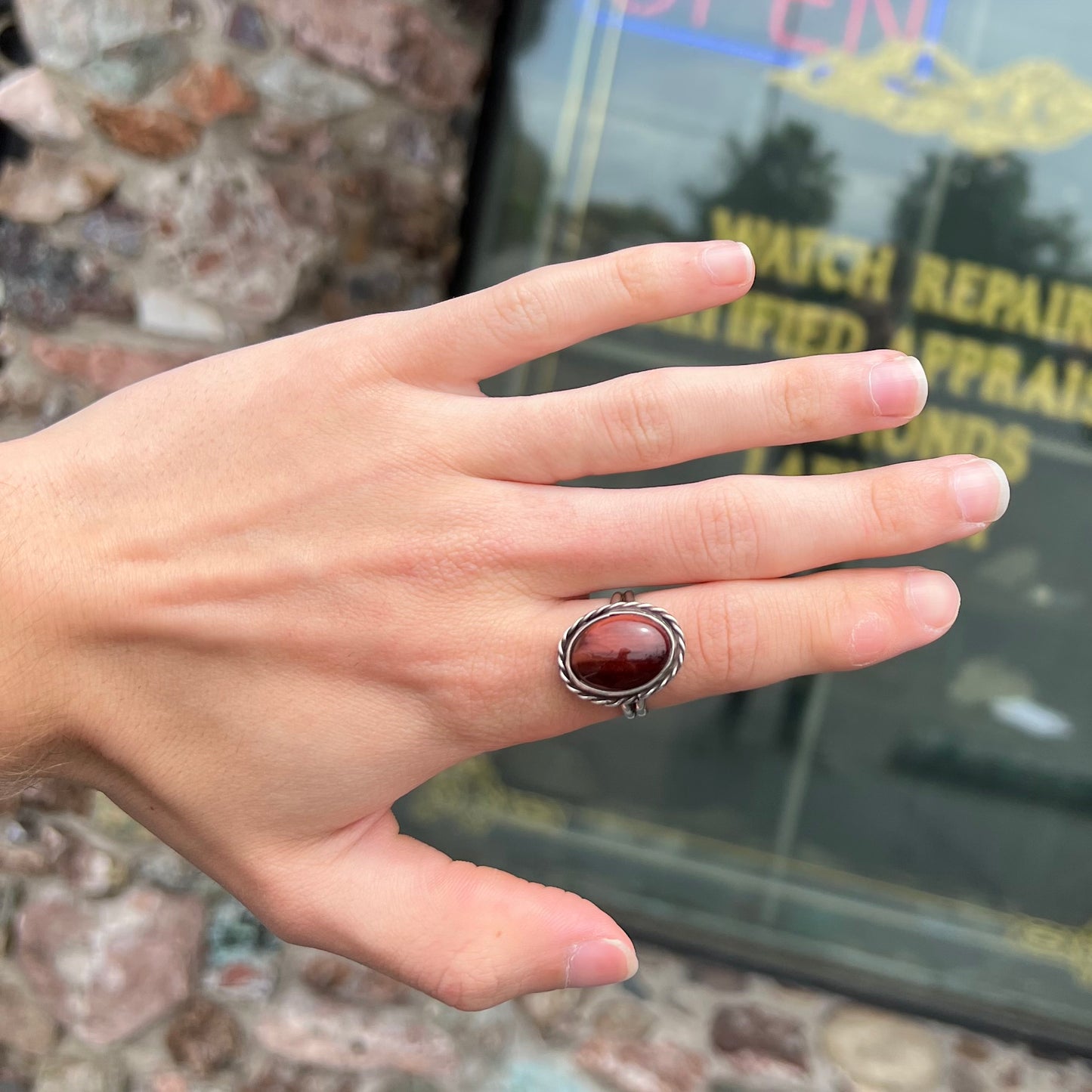 A men's sterling silver rope bezel ring set with a red tiger's eye stone.