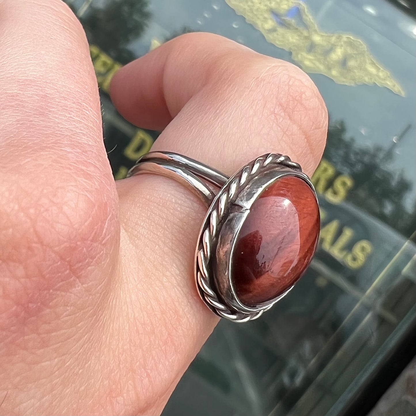 A men's sterling silver rope bezel ring set with a red tiger's eye stone.