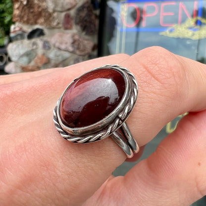 A men's sterling silver rope bezel ring set with a red tiger's eye stone.