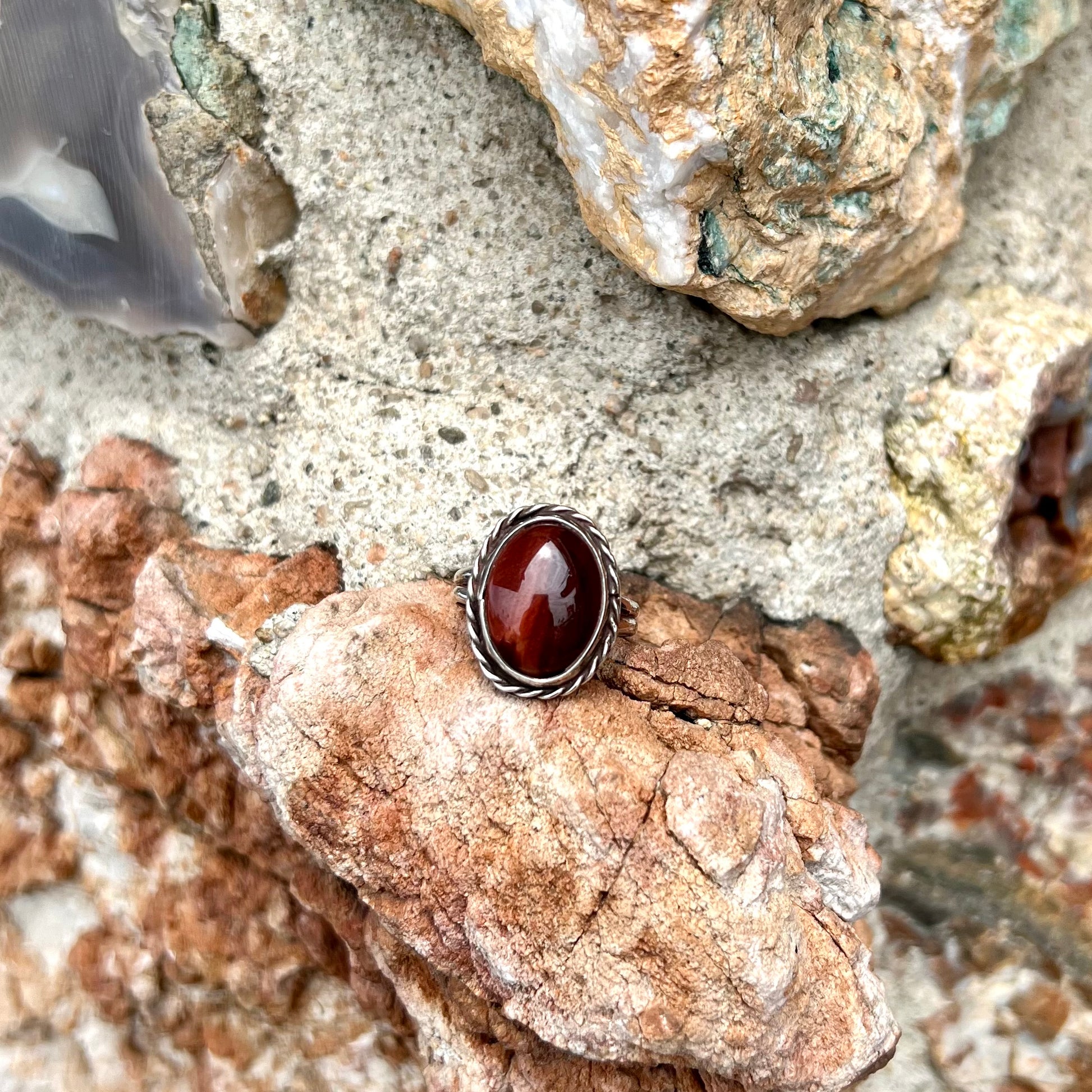 A men's sterling silver rope bezel ring set with a red tiger's eye stone.