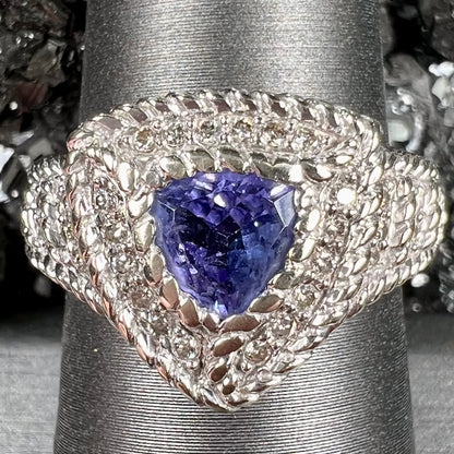 A white gold trillion cut tanzanite ring set with a diamond halo and diamond accents.