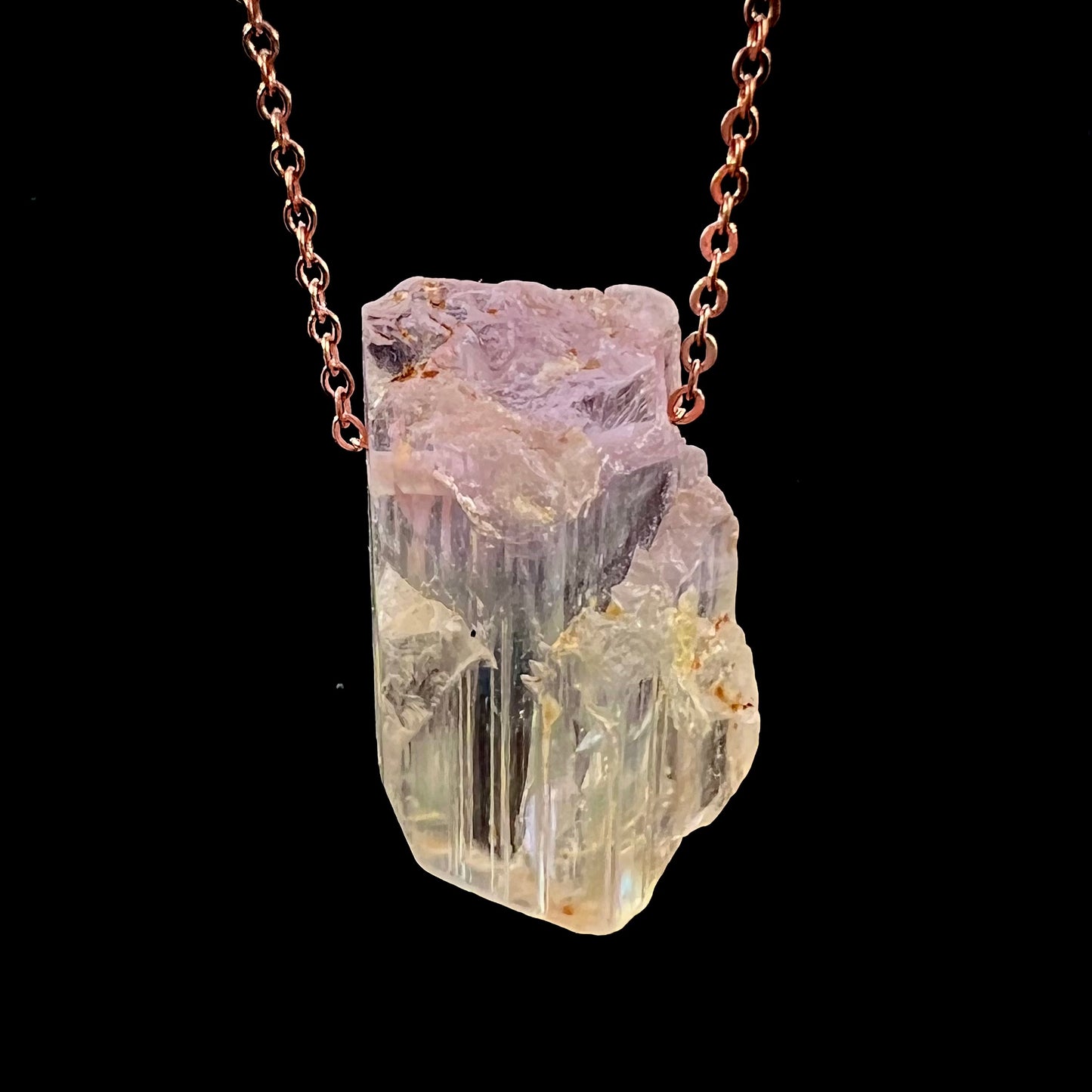 A drilled bicolor spodumene crystal hanging on a copper cable chain.  The crystal is pink and yellow, or kunzite and triphane respectively.