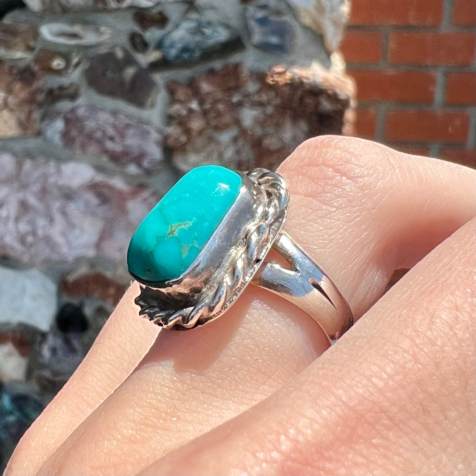 A sterling silver turquoise split shank ring.  There is a handmade silver rope around the turquoise.