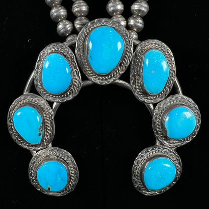 A handmade, sterling silver, Navajo Sleeping Beauty turquoise squash blossom necklace.