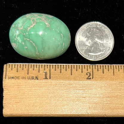 A loose, oval cabochon cut green variscite stone from Utah, USA.