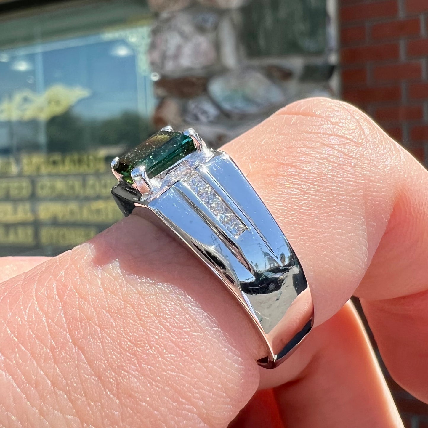 An 18k white gold green tourmaline and diamond men's ring.  The stones are princess cut.