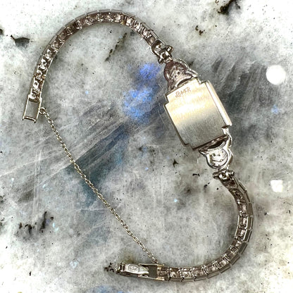 A vintage, art deco style white gold and diamond bracelet set with a rectangular shape black boulder opal stone.