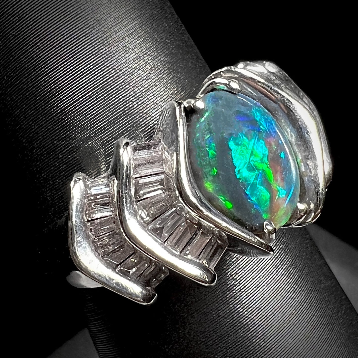 A white gold ring set with a Lightning Ridge natural black opal and baguette cut diamonds.