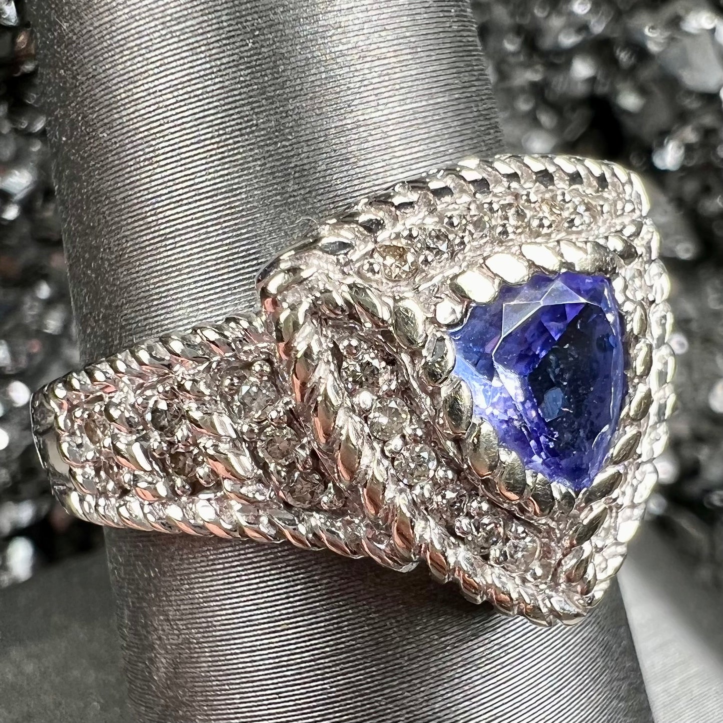 A white gold trillion cut tanzanite ring set with a diamond halo and diamond accents.