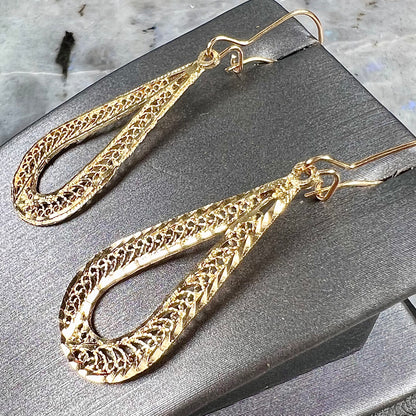 A pair of pear shape yellow gold filigree dangle earrings.