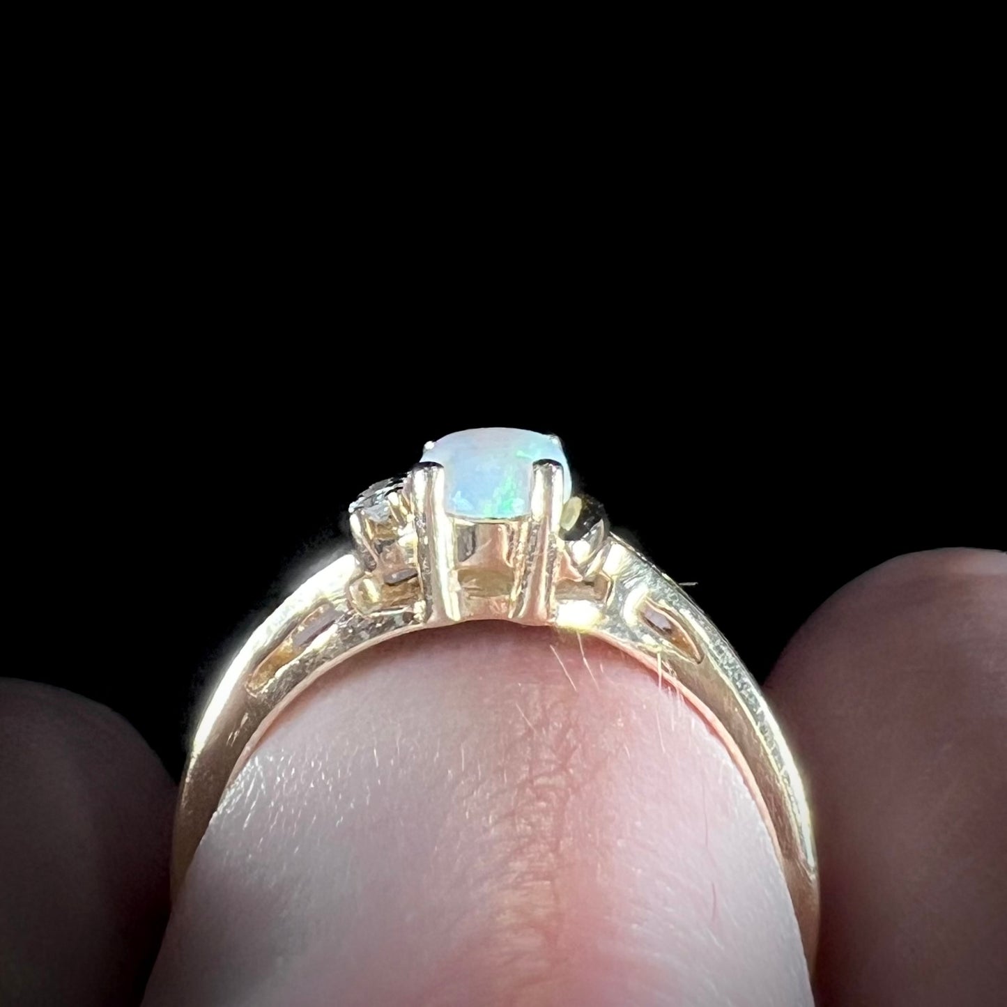 A ladies' yellow gold Coober Pedy, Australian opal ring set with three round cut diamonds.