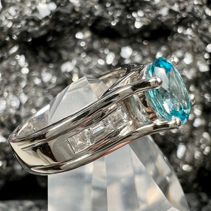 A sterling silver ring set with an oval cut blue zircon center stone and channel set white zircon accents.