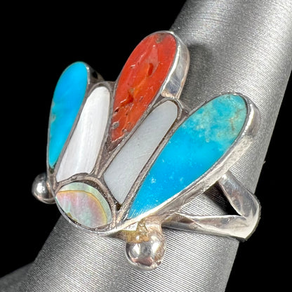 A turquoise, coral, and mother of pearl stone inlay ring made in the motif of a Zuni Indian headdress.