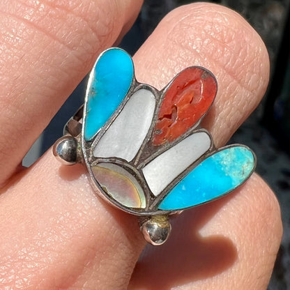 A turquoise, coral, and mother of pearl stone inlay ring made in the motif of a Zuni Indian headdress.